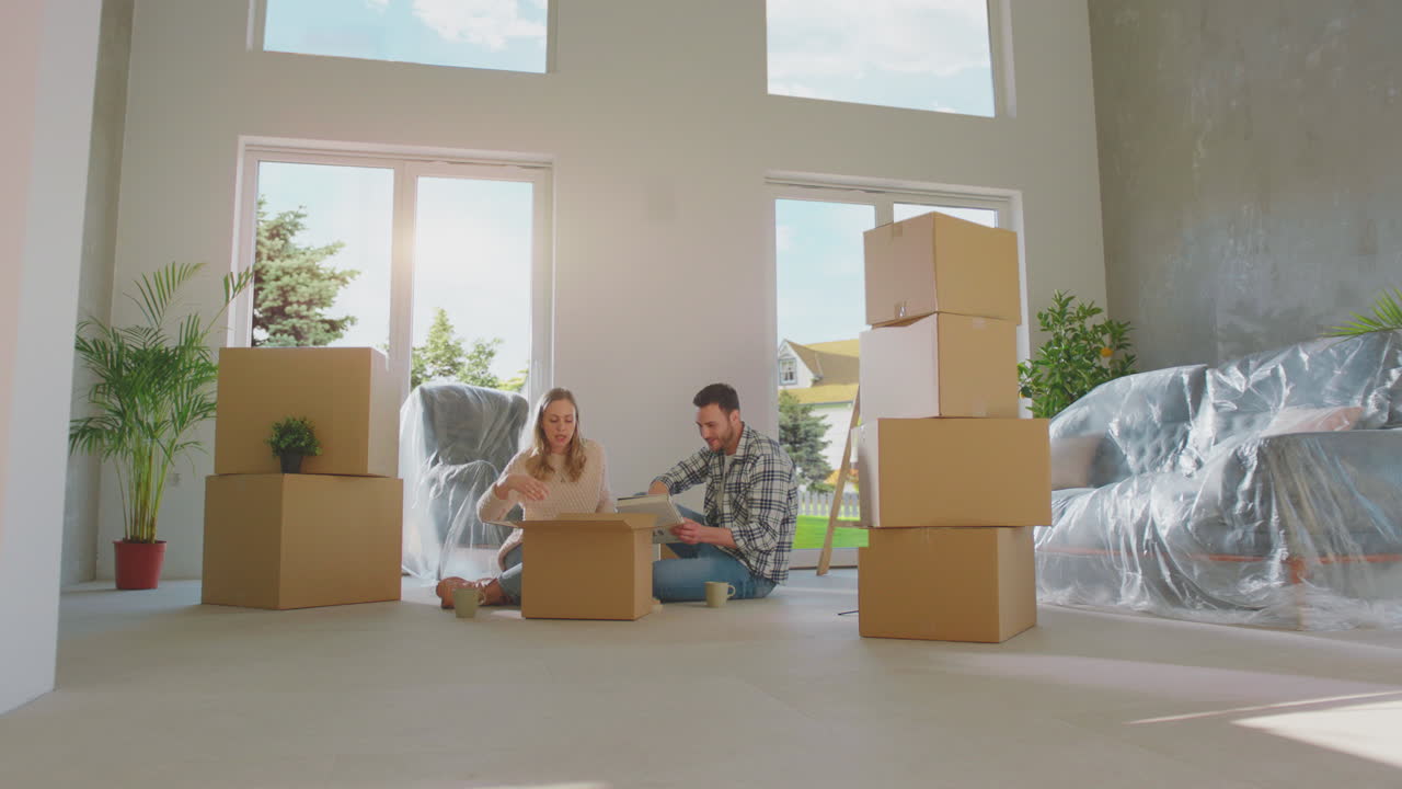 una pareja joven desempaquetando una nueva caja de cartón.