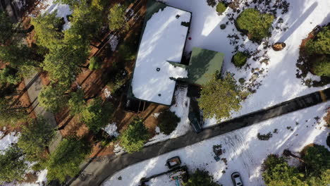 vehicle leaving modern house in woods in winter season, aerial top down view