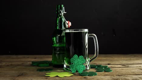 cerveza verde, botella y tréboles en una mesa de madera para st. patrick