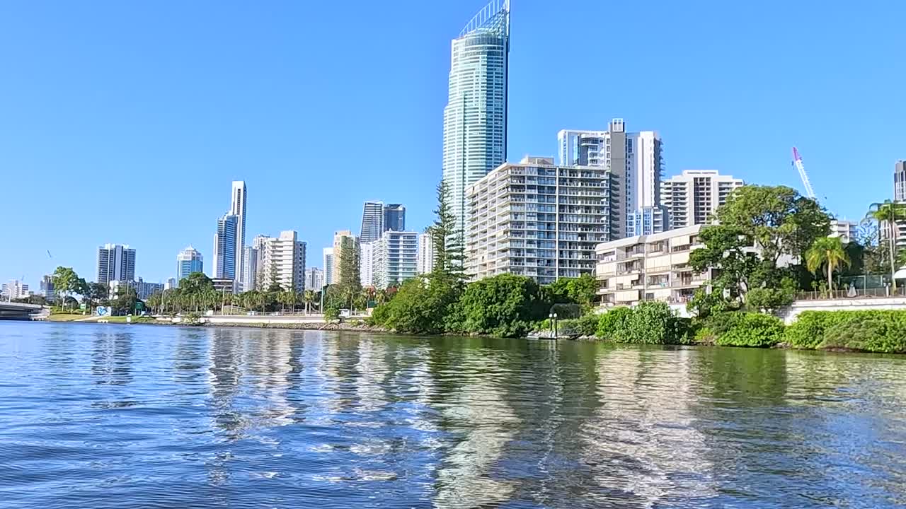 Explore the serene riverfront with towering skyscrapers and modern bridges under a clear blue sky.