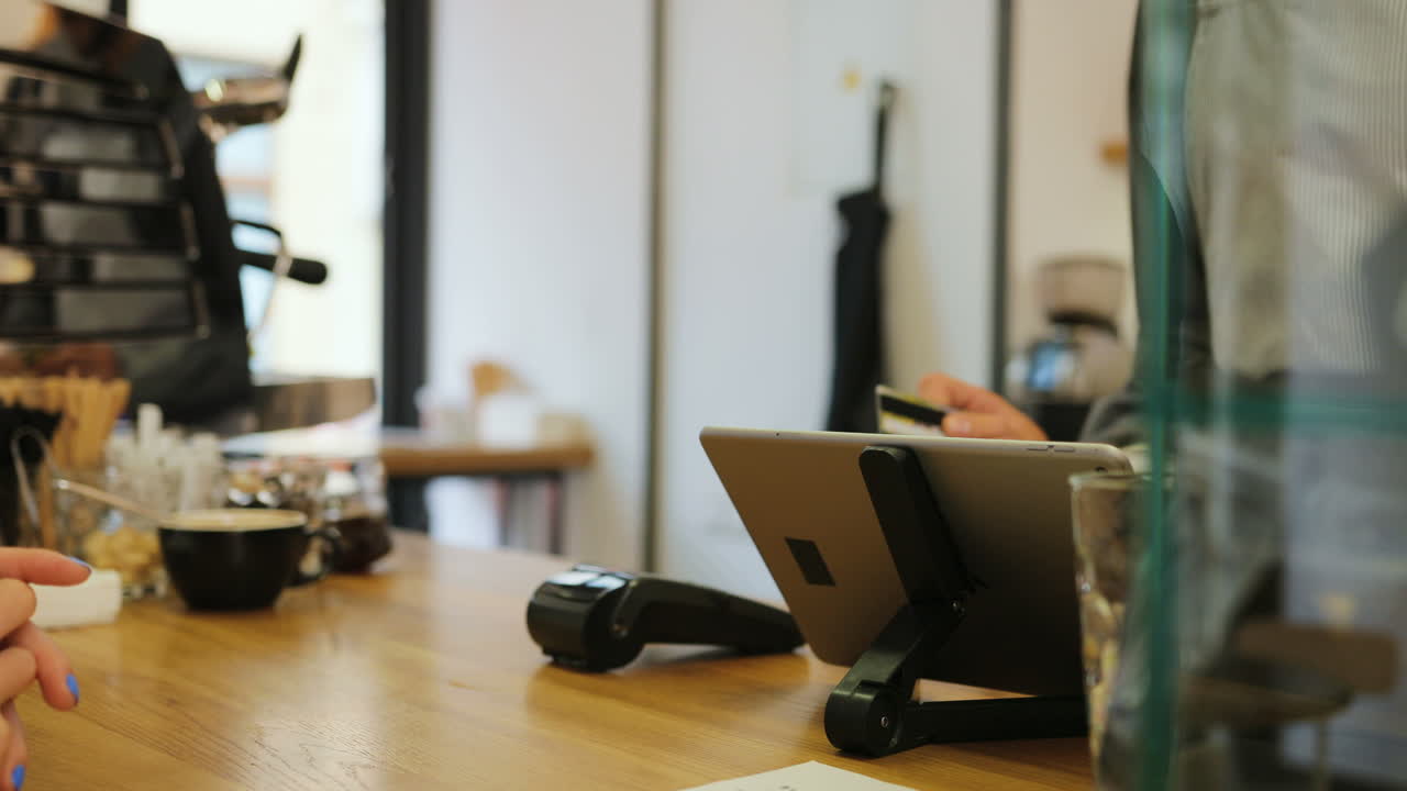 커피숍에서 바리스타의 도움을 받아 신용카드로 커피값을 지불하는 여성 손의 클로즈업 보기