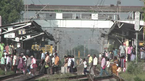 Crowds-of-people-walking-across-a-trainstation's-tracks