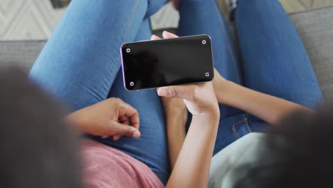 madre y hija afroamericanas usando un teléfono inteligente con espacio de copia en la pantalla