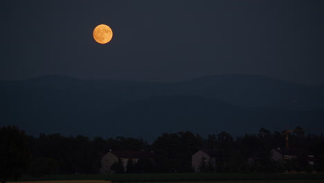 luna llena sobre las montañas y las casas