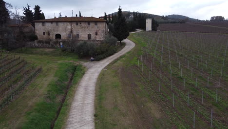 Frescobaldi-vineyard-aerial-view-along-pathway-above-farmhouse-to-reveal-Chianti-winemaking-hillside-growth