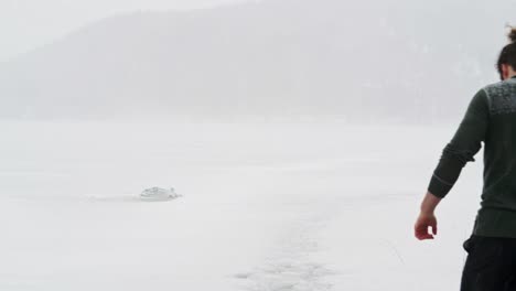 guy walking on deep snow leaving footprints behind on a snowstorm near trondheim in norway
