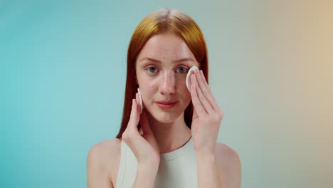 woman cleansing face with cotton pads