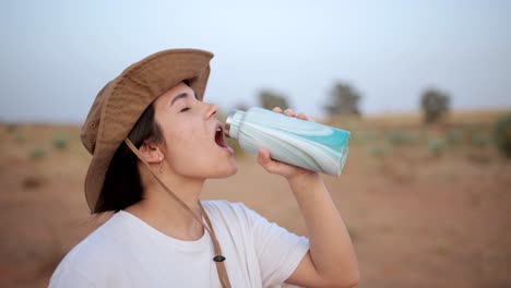 woman drinking water in desert field