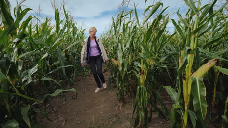 young active girl in a pink raincoat having fun among the tangled corn maze