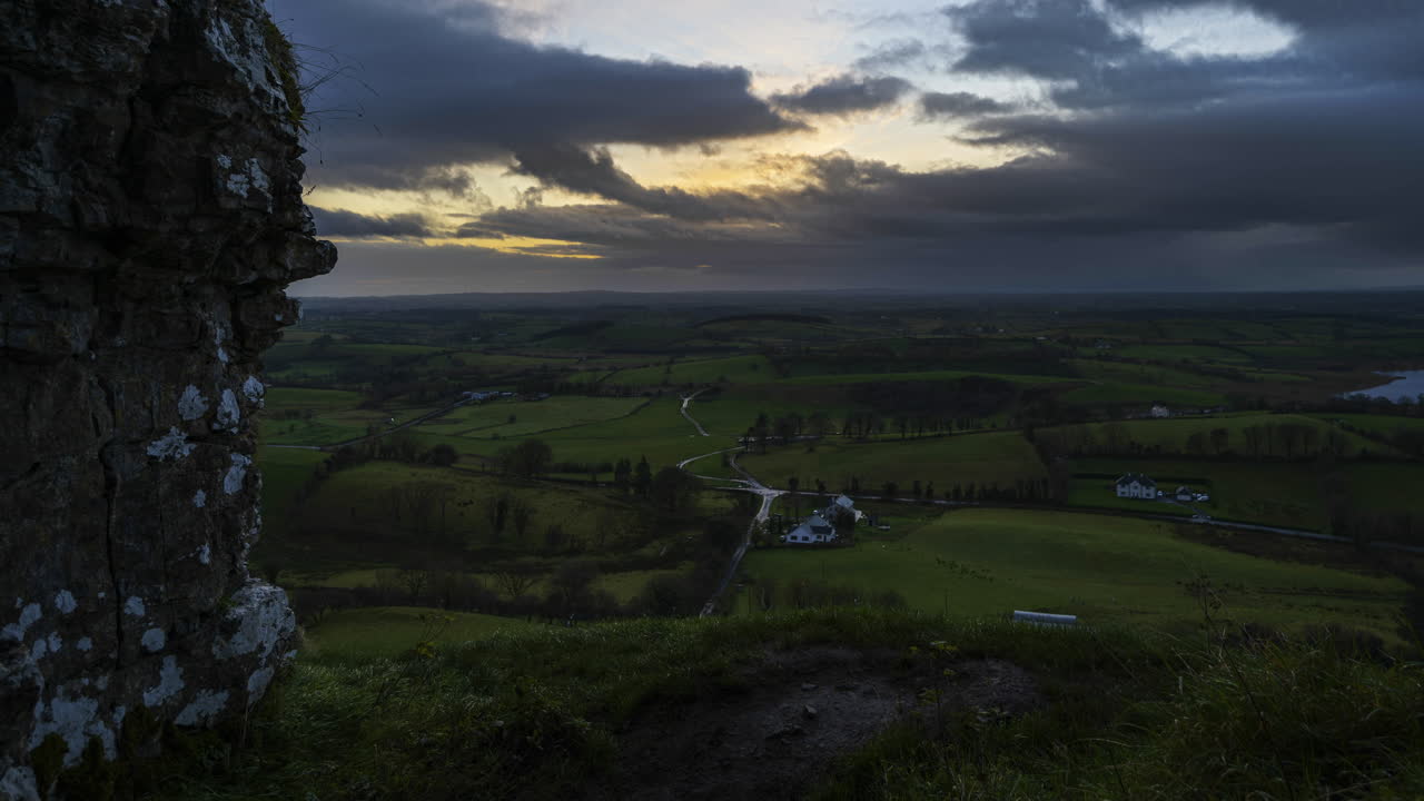 lapso de tiempo del paisaje agrícola rural con campos de hierba y colinas durante la puesta de sol nublada vista desde las cuevas de keash en el condado de sligo en irlanda