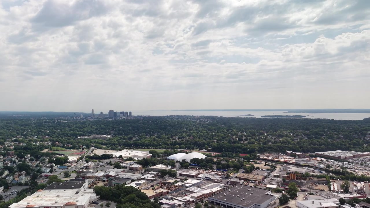Ampie riprese aeree che mostrano il paesaggio urbano di New Rochelle, con i suoi diversi edifici e spazi verdi, che conducono allo skyline distante della città che confina con il vasto Long Island Sound