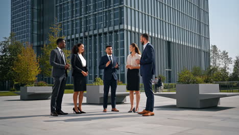 group of diverse business professionals having an outdoor meeting in front of a modern office building