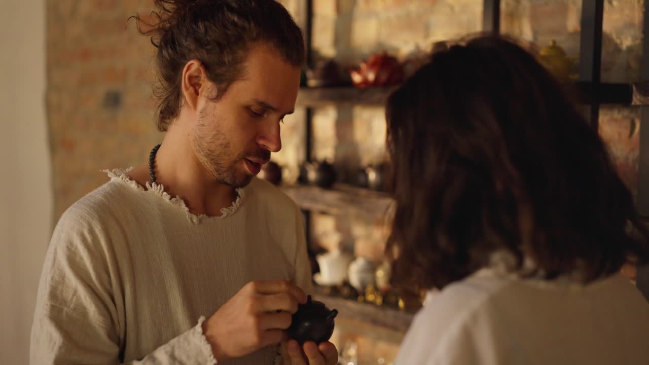 한 남녀가 작은 검은 차병을 보고 있다