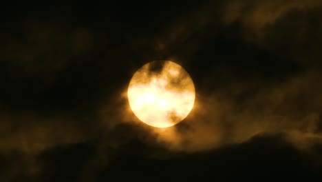 yellow moon or sun seen through dark clouds with birds quickly flying in front