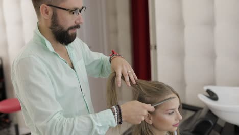 professional hairdresser styling combing model hair. beautiful woman in salon