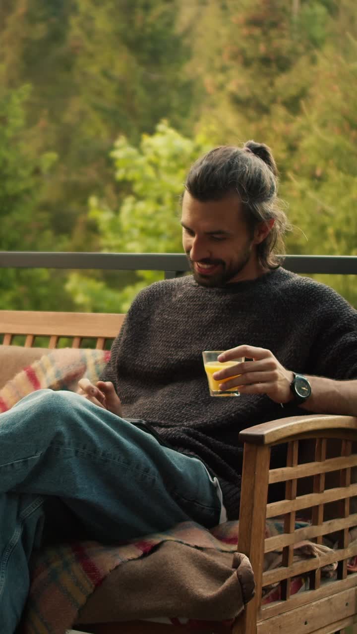 Uomo che si rilassa su una terrazza con un succo e il telefono