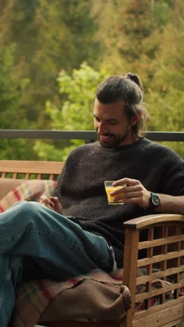 man relaxing on patio with juice and phone