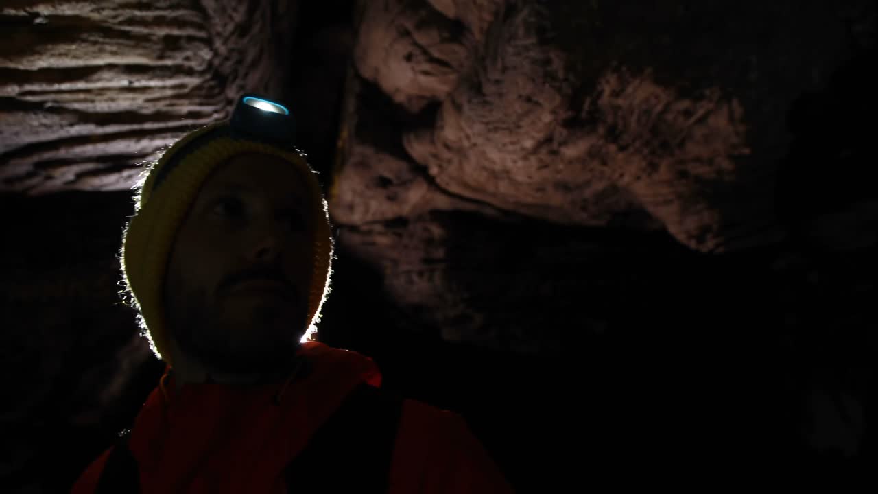 어두운 동굴을 탐험하는 남성 하이커 4k