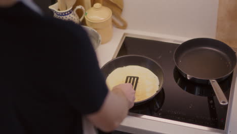 el hombre da la vuelta a la tortilla en la sartén en primer plano.