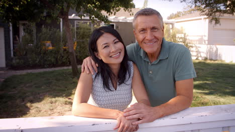 portrait of mature couple looking over back yard fence