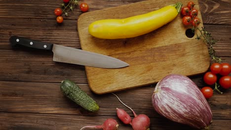 Berenjena-Amarilla-En-Una-Tabla-De-Madera-Mientras-Prepara-Alimentos-Saludables-Con-Verduras,-Tiro-De-Arriba-Hacia-Abajo