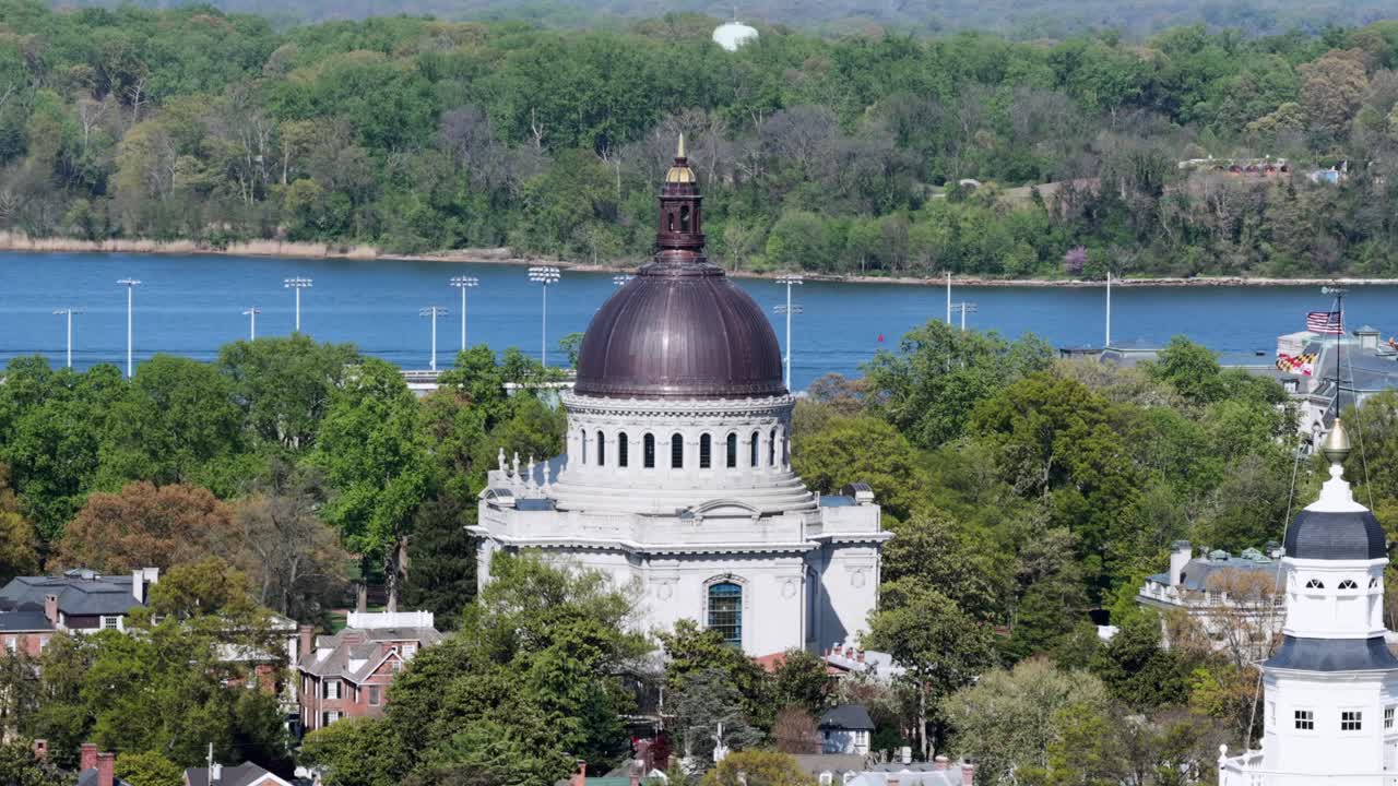 Vista aérea orbital de la histórica Annapolis, Maryland, con la cúpula de una iglesia sobre barrios arbolados, con el frente marítimo y aguas azules tranquilas brillando bajo el brillante sol de primavera. Ciudad pacífica en EE. UU.