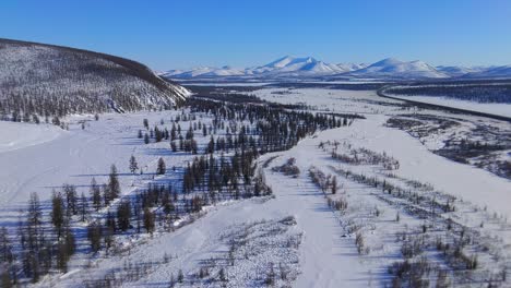 frozen river against the backdrop of mountains and trees in yakutia from a 4k drone