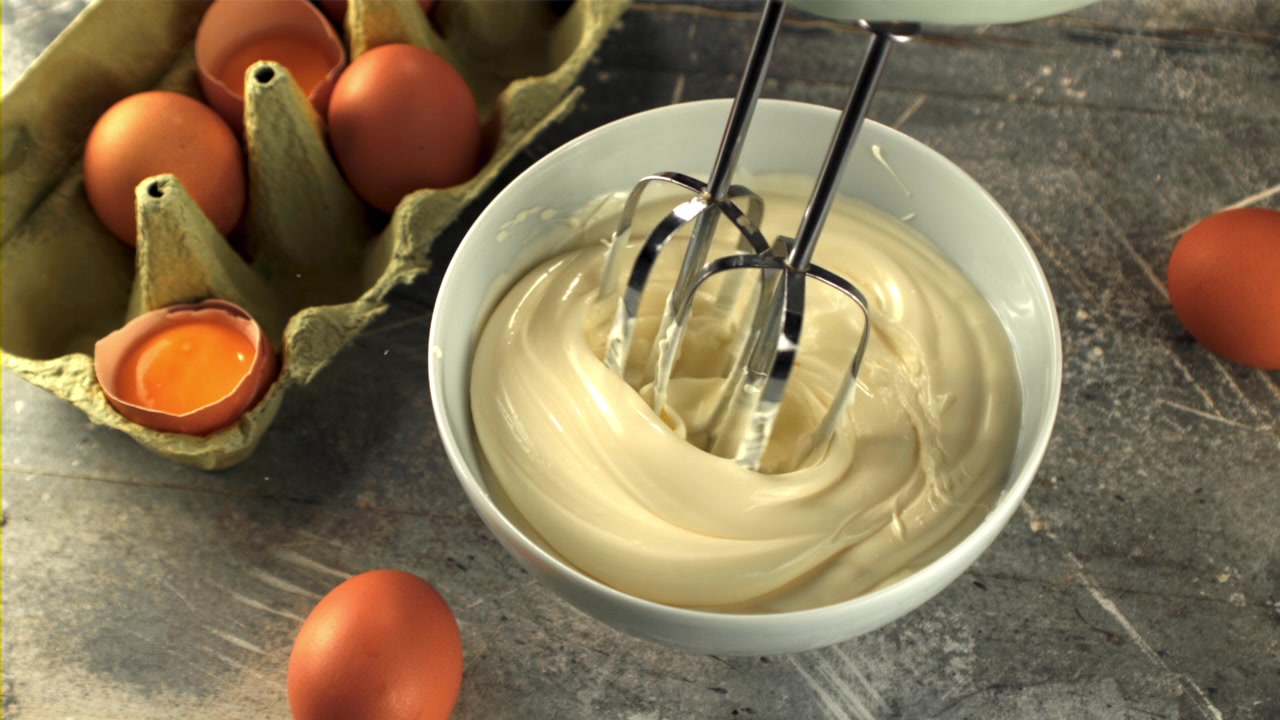 Hand Mixer Blending Creamy Mayonnaise in a Bowl with Fresh Eggs