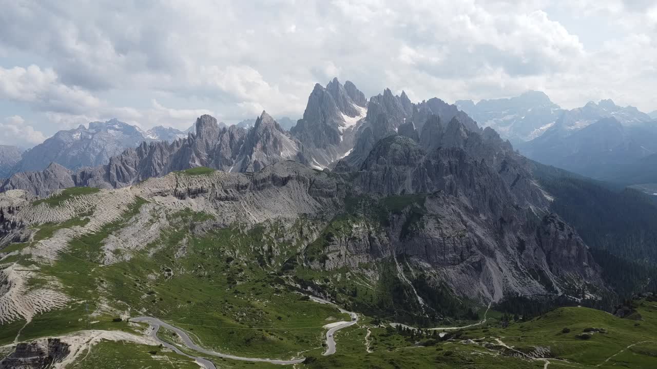 Smooth drone footage of a scenic hiking path leading to the Tre Cime hut, surrounded by breathtaking mountain views.