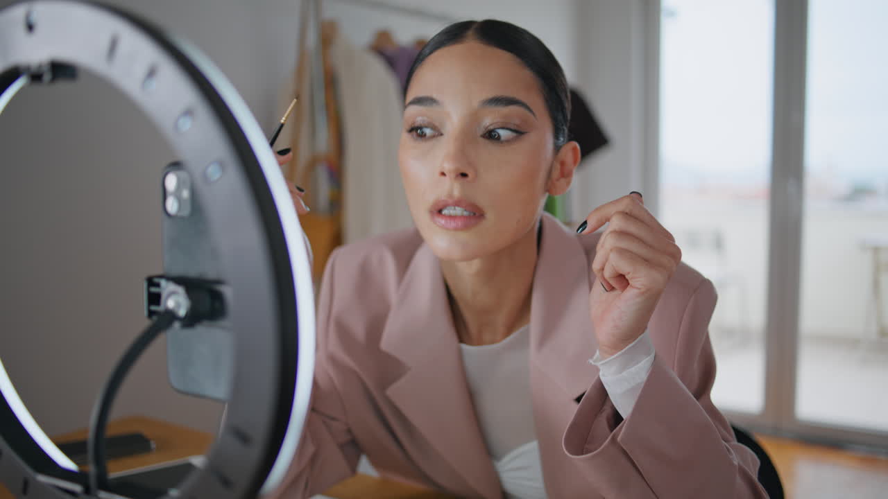 blogger chica aplicando delineador de ojos buscando teléfono en el hogar primer plano. mujer grabando blog