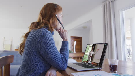 mujer caucásica con auriculares de teléfono haciendo una videollamada con una colega en una computadora portátil en casa
