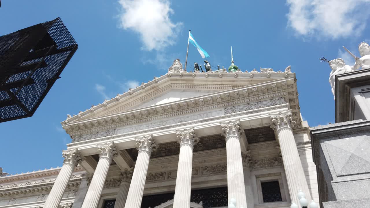 Low angle view at Argentine National Flag and congress grand architecture over sunny sky and Lola Mora neoclassical statues