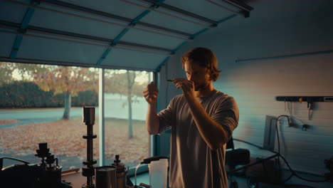 Man Meticulously Examines an Object in a Garage Workshop