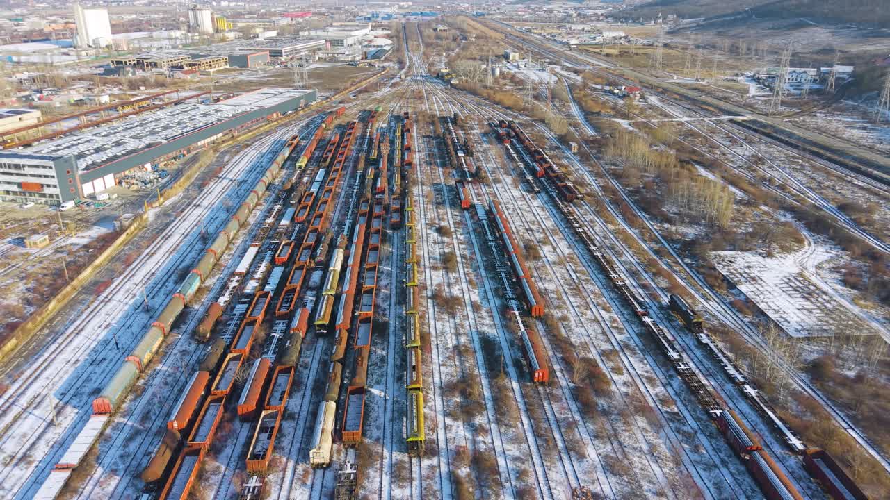 Drohnenaufnahme eines Güterzug-Lagerbereichs in der Nähe von Iași. Mehrere Linien mit stehenden Güterwaggons, mehrfarbig, auf schneebedeckten Gleisen im Winter