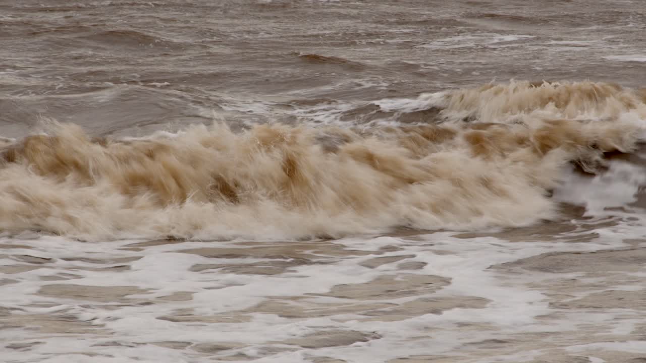 추운 겨울의 파도가 ingoldmells, skegness 모래 해변에 부 ⁇ 히고 있습니다.