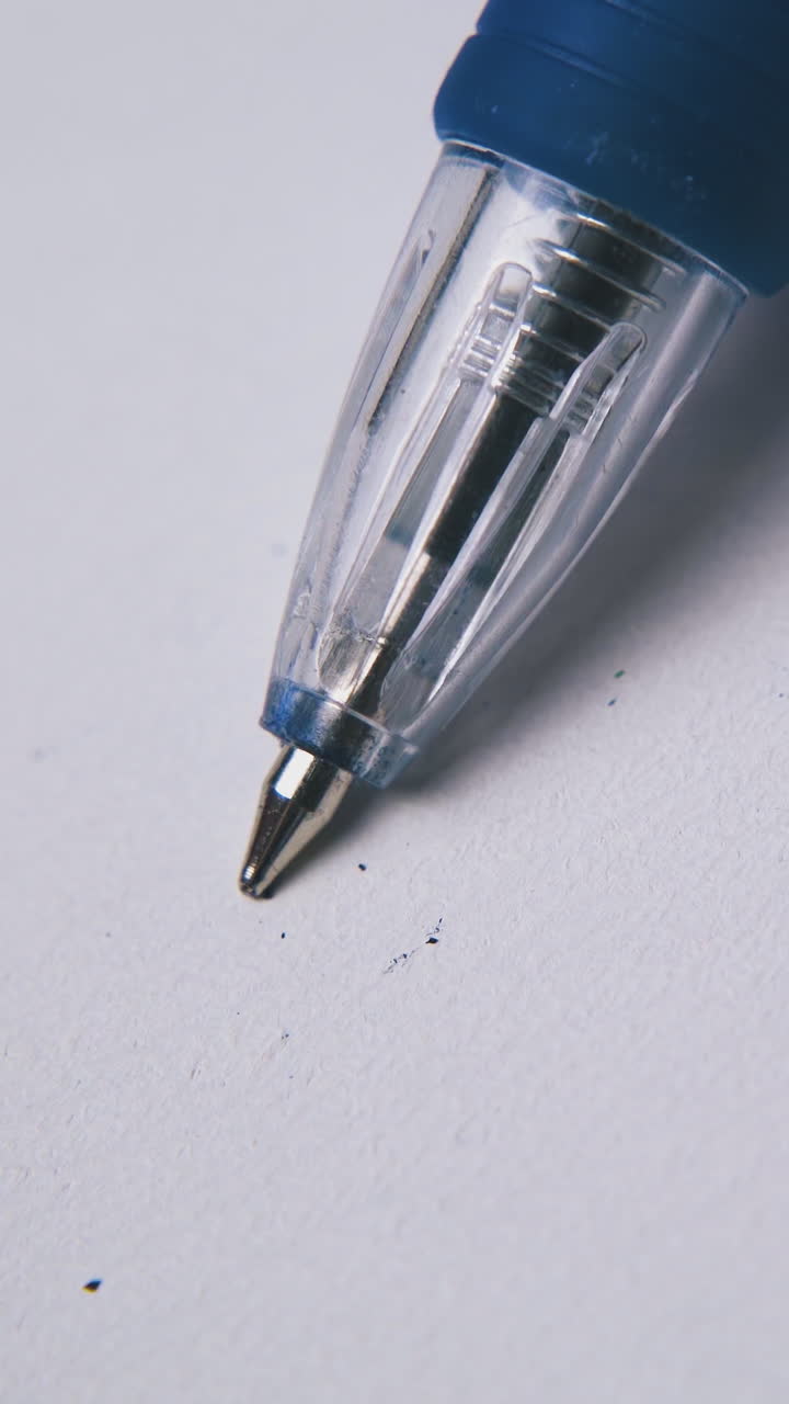 clicking blue automatic pen in plastic and rubber case above white empty paper sheet extreme close view