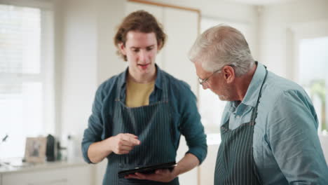 man teaching his grandson how to cook using a tablet