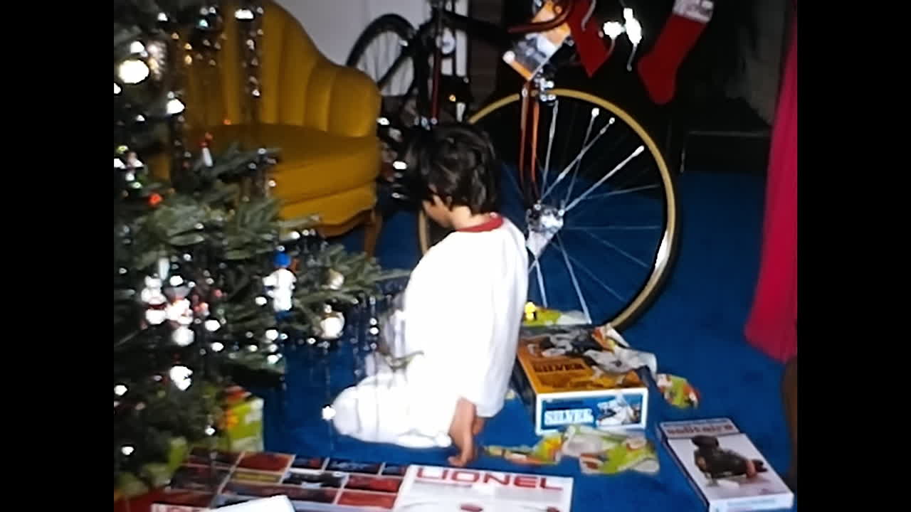 Little Boy Standing in Front of Christmas Tree. CIRCA USA - 1970s: A little boy stands in front of a Christmas Tree in a 1970s video archive from the USA.