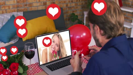 heart icons over caucasian man showing a ring while having a video call on laptop