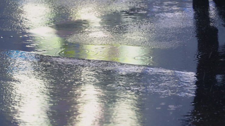 Shadow Reflection Of A Walking Person Through Rain Puddles On Pavement Road At Night In Tokyo, Japan