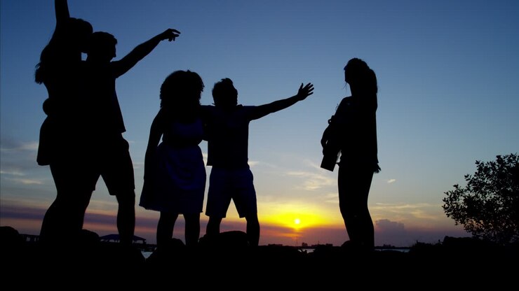Silueta de personas con guitarra en una playa al atardecer