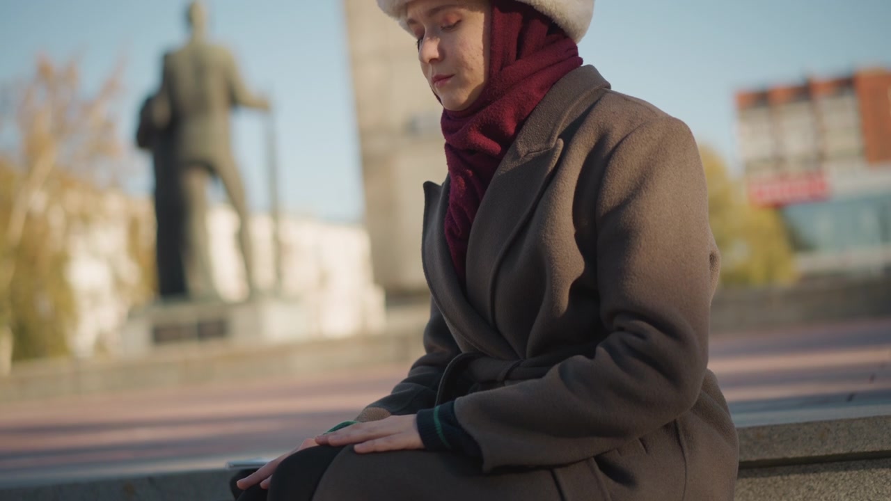 Donna con cappotto invernale e cappello di pelliccia seduta all'aperto