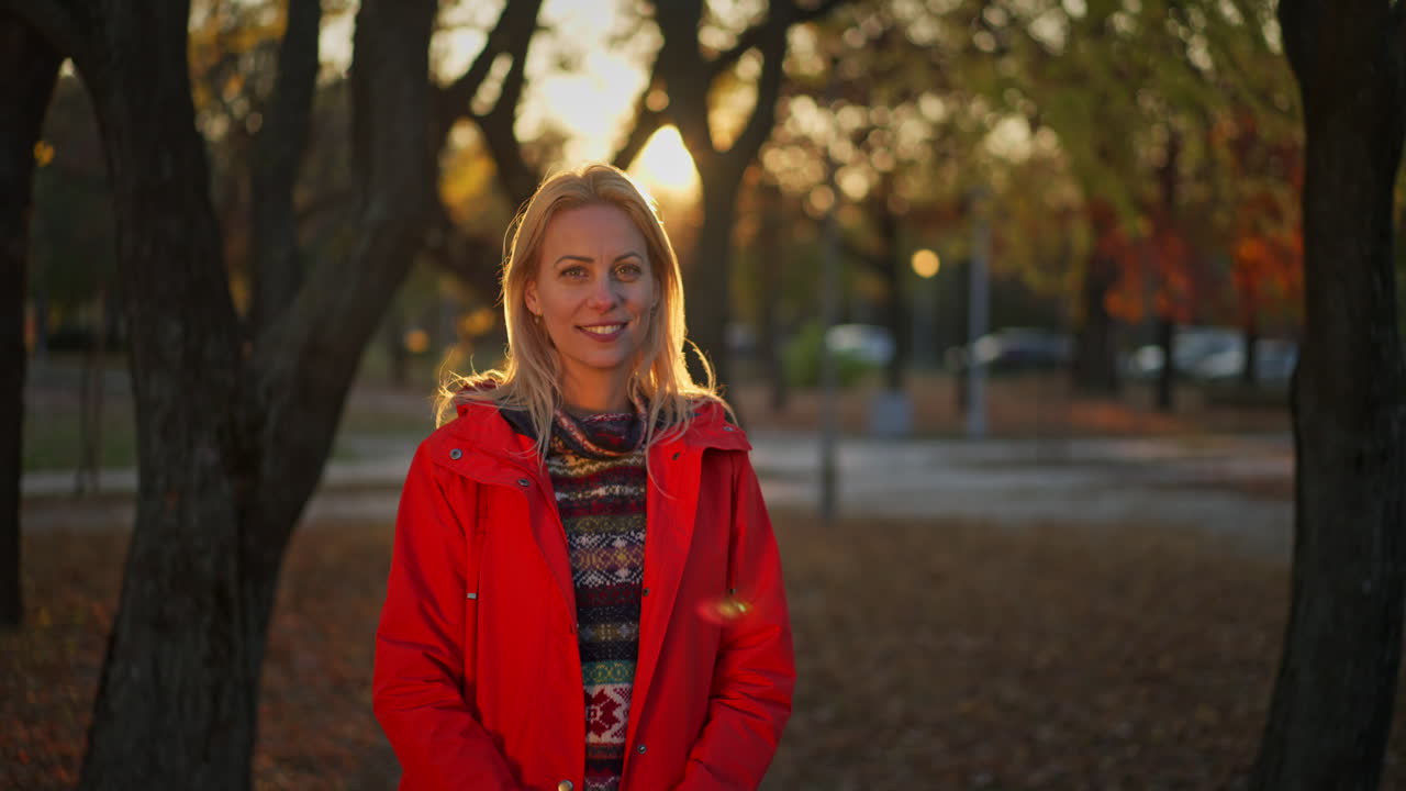 Portrait of a smiling woman in a red coat in an autumn park