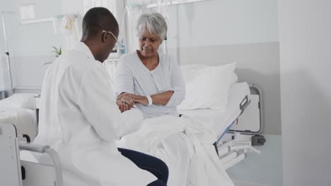 diverse female doctor inspecting arm of concerned senior female patient, slow motion