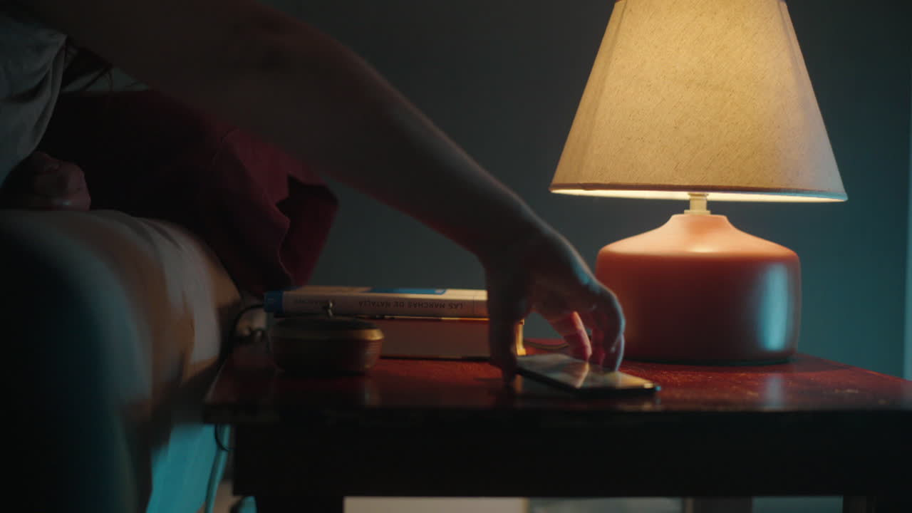 Woman reaching for a lamp in a bedroom