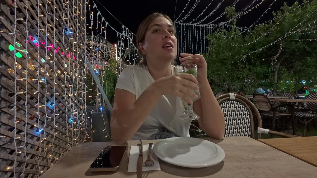 Young Woman Enjoying a Refreshing Cocktail at a Night Cafe