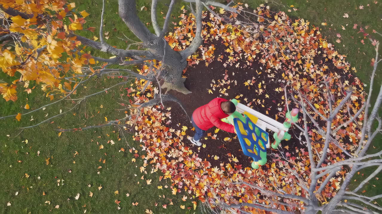 Overhead view of a child playing on a playground slide in autumn leaves