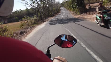 driving slowly relaxing on bali indonesia road adventure on motorbike. riding to find some fun beach and ocean view. transportation system mainly motorcycle.