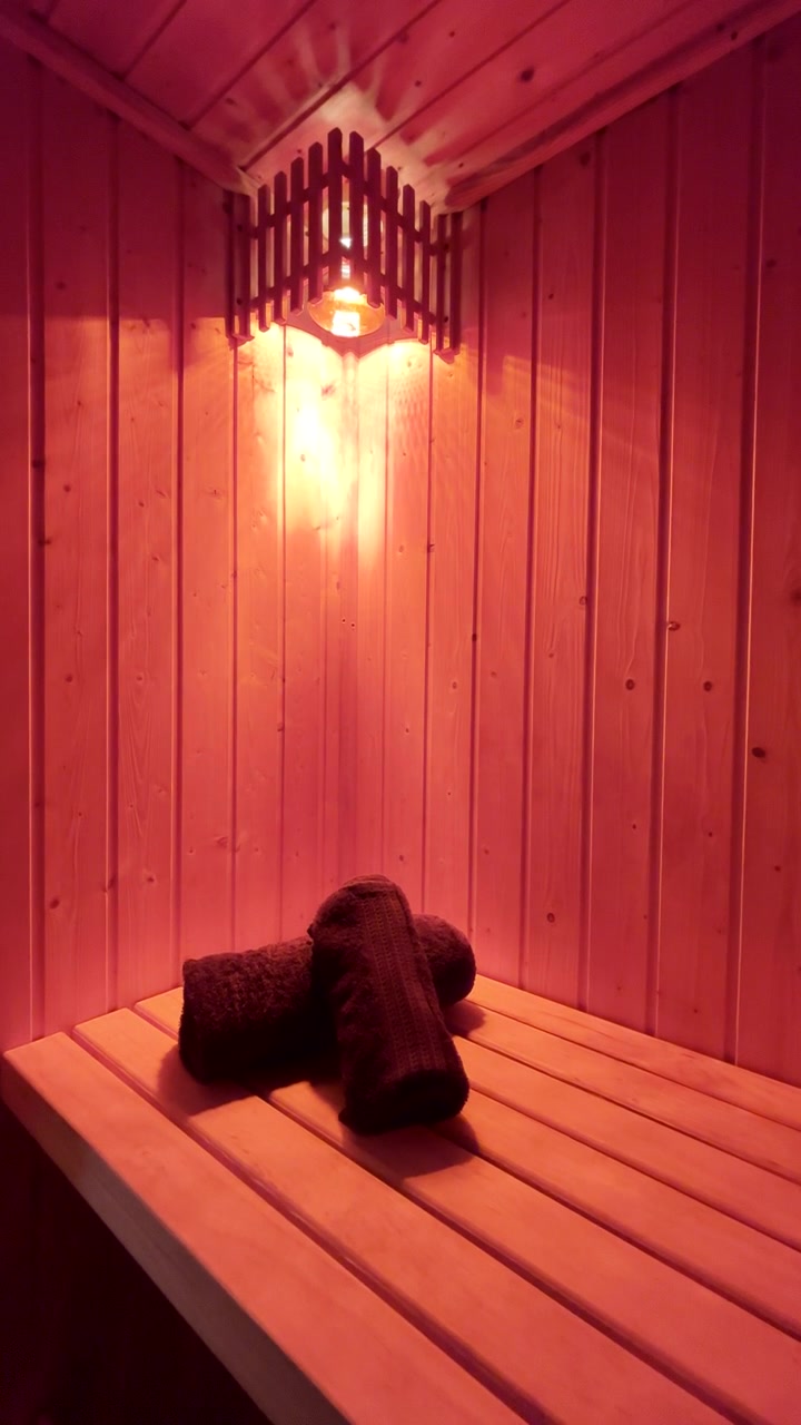 Verticale. Luce rossa sopra due asciugamani piegati illumina una sauna in legno