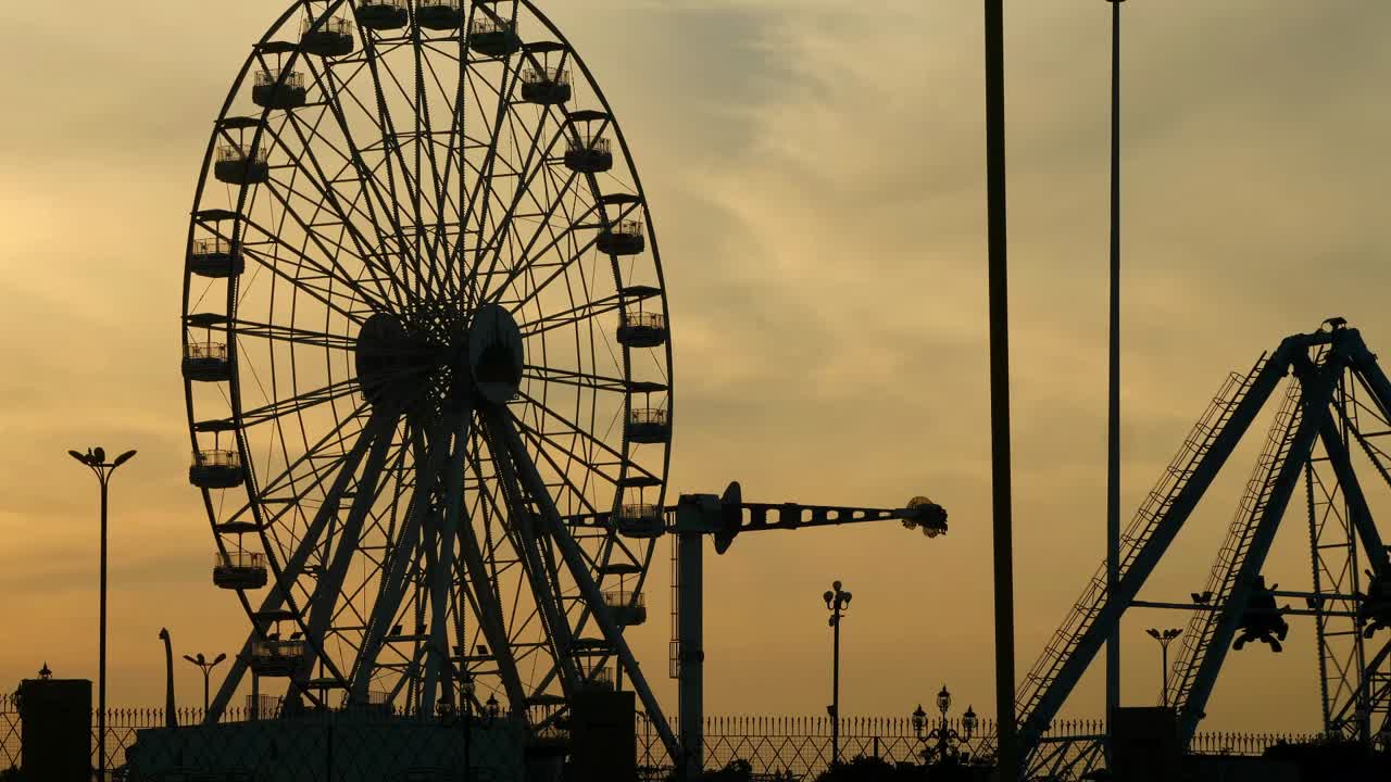 rueda de la fortuna del parque de atracciones silueta contra el cielo naranja del atardecer